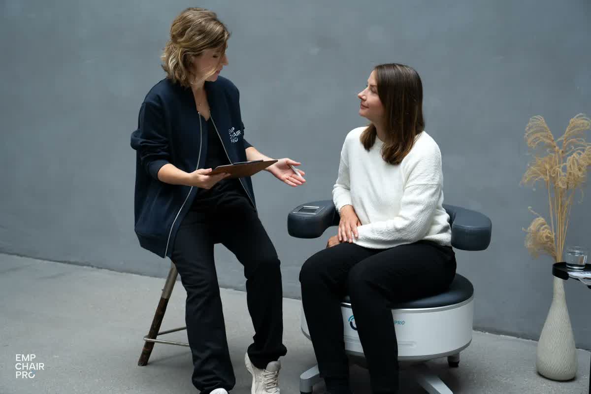 Beraterin mit Tablet im Gespräch mit einer Kundin, die auf dem EMP Chair Pro sitzt