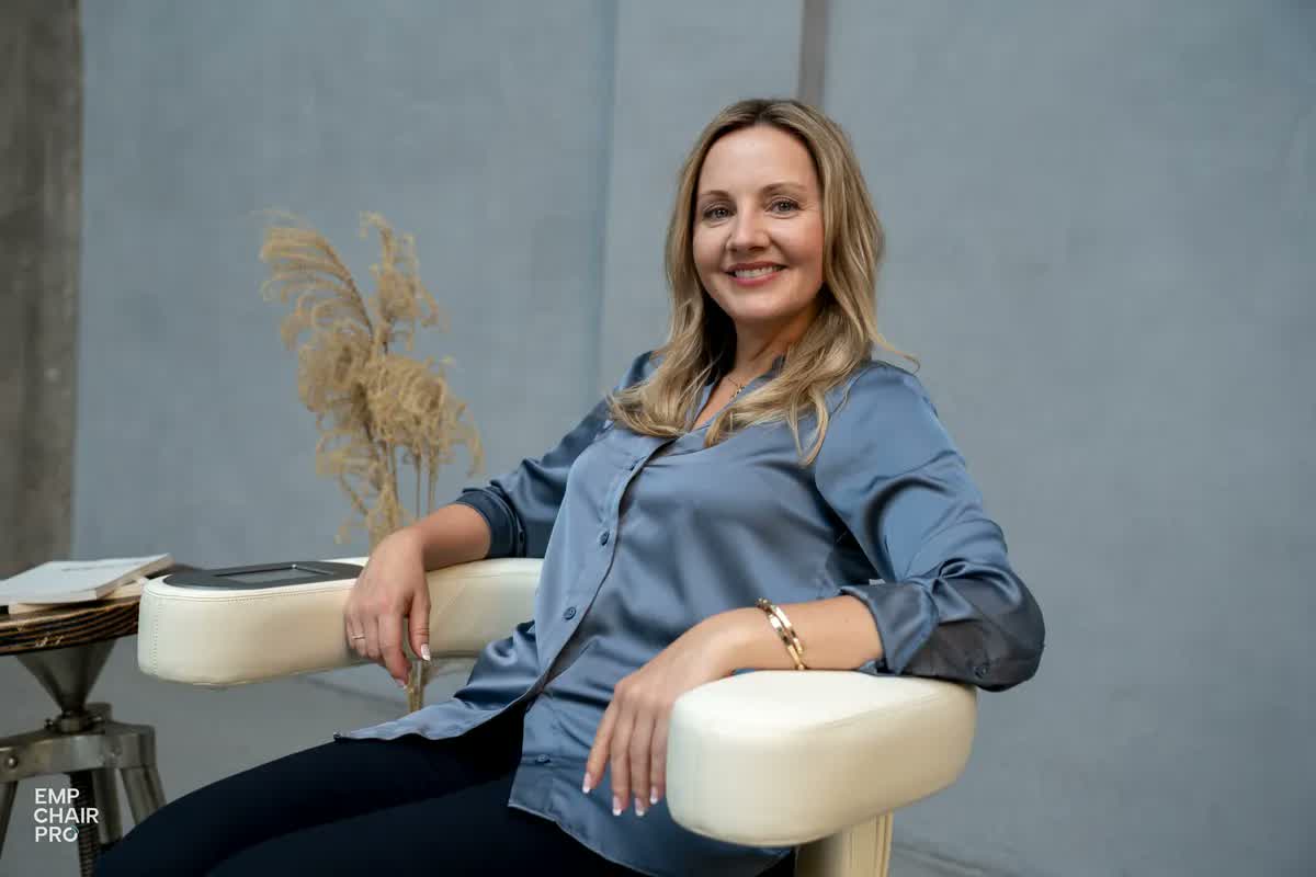 Frau in blauer Bluse sitzt lächelnd auf dem EMP Chair Pro