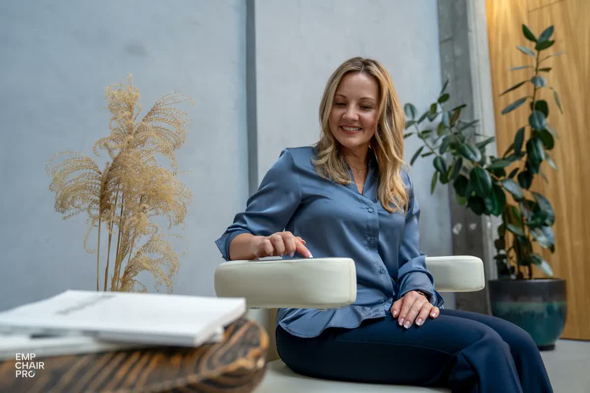 Frau in blauer Bluse sitzt auf dem EMP Chair Pro und bedient das Bedienfeld