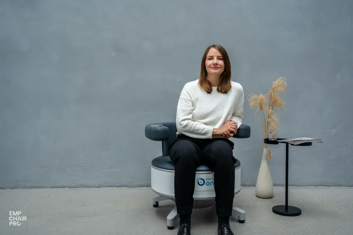 Frau sitzt in Pullover und Hose auf dem EMP Chair Pro
